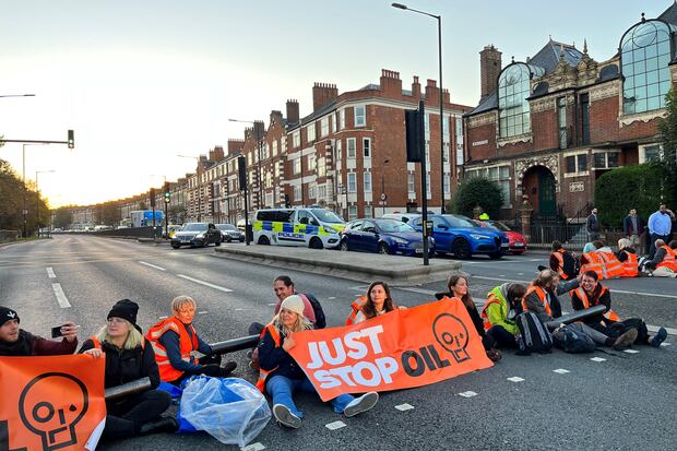 Activistas de Just Stop Oil sostienen una pancarta en Barons Court, en el oeste de Londres, mientras bloquean una autopista. (Foto: AFP)